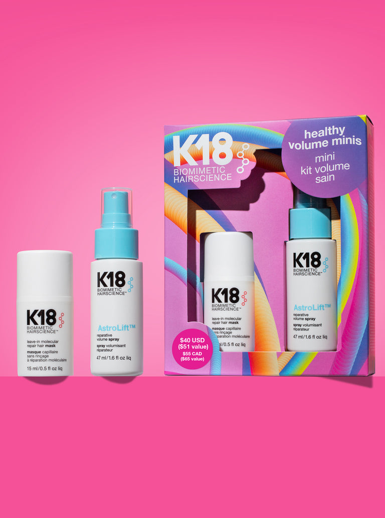 K18 hair care products including bottles and a box on a pink background