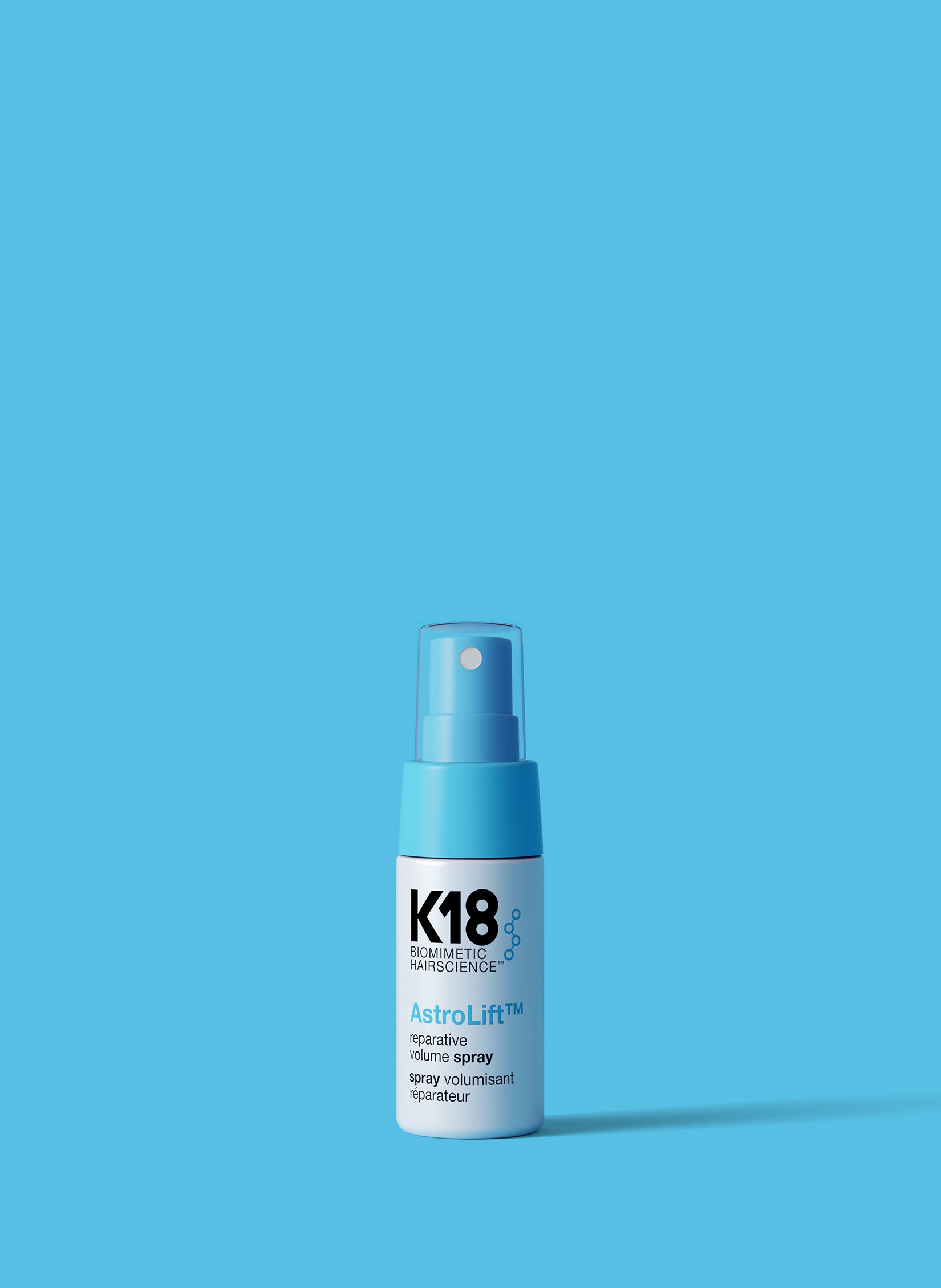 White and light blue bottle of Astrolift reparative volume spray on a blue background. 