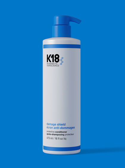K18 conditioner bottle on a blue background