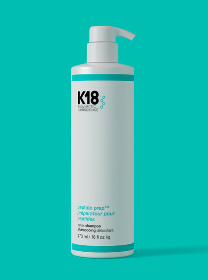 K18 hair Jumbo Detox shampoo bottle on a teal background. 