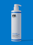 K18 shampoo bottle on a blue background