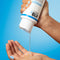 Hand holding a K18 product with clear liquid being dispensed against a blue background