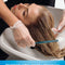 Person getting hair washed with a focus on hair care product benefits.