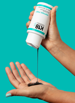 Hands pouring the clarifying detox shampoo into hand on teal background. 