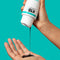 Hands pouring the clarifying detox shampoo into hand on teal background. 