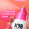 K18 heat protectant and conditioning spray with a hand holding the bottle against a pink background